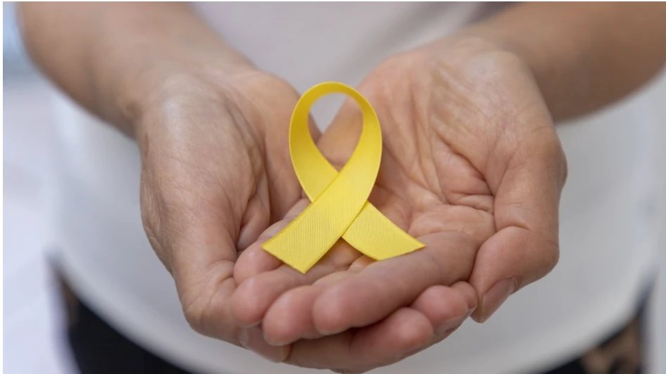 A pair of cupped hands holding a yellow suicide prevention awareness ribbon